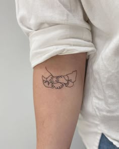 a woman's arm with a tattoo on it that has two hands holding each other