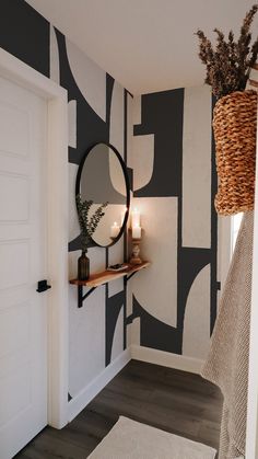 a room with black and white wallpaper has a round mirror on the wall next to a wicker basket