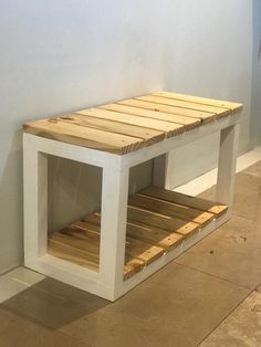 a wooden bench made out of pallets in a room with white walls and tile flooring