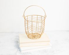 a wire basket sitting on top of a white book next to a stack of books