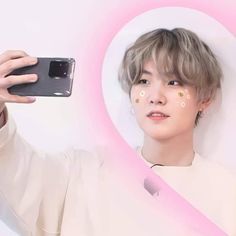 a person taking a selfie with an apple logo in front of them and a pink background