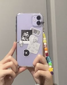 someone is holding up their phone case with stickers on it, and there are other things in front of them