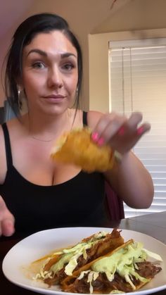 a woman is eating some tacos and chips at the table in front of her