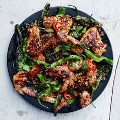 a black plate topped with chicken and veggies