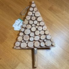 a christmas tree made out of logs on a wooden floor with a price tag attached to it