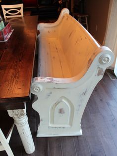 an old wooden bench sitting on top of a hard wood floor next to a table