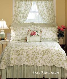 a bed with a white and green comforter on top of it next to a window