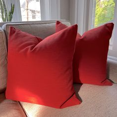 two red pillows sitting on top of a couch