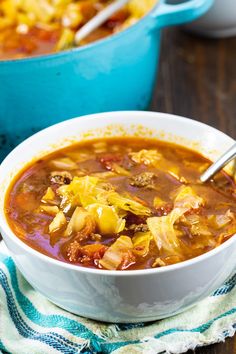 a white bowl filled with cabbage and beef soup on top of a blue dish towel