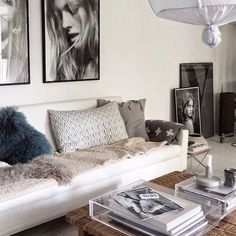 a living room filled with white furniture and pictures on the wall above it's coffee table