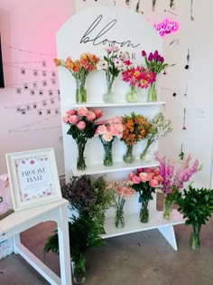 flowers are displayed in vases on shelves at a flower shop with pink and orange flowers