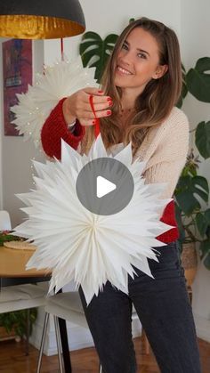 a woman holding a white paper flower in her hands