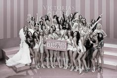 a group of women standing next to each other in front of a wall with words victoria's secret