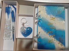 an open box containing a blue heart and keychain with glitters on it