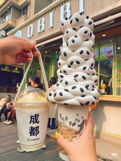 a person holding an ice cream sundae in front of a building with chinese writing on it