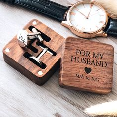 a wooden watch and cufflinks are sitting on a table next to each other