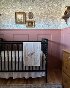 a baby's crib in the corner of a room with pink walls and floral wallpaper