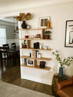 a living room filled with furniture next to a dining room table and chairs in front of a white wall