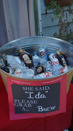 a bucket filled with lots of bottles of beer sitting on top of a red table