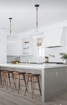 a kitchen island with stools in front of it and two lights hanging from the ceiling