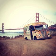 an old rusty bus sitting in front of the golden gate bridge