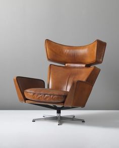 a brown leather chair sitting on top of a white floor next to a gray wall