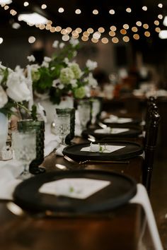 a long table with plates and vases filled with white flowers on top of it