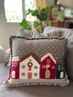 a close up of a pillow on a bed with a house design and christmas decorations