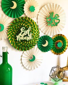 green and white paper fans are hanging on the wall next to a vase with flowers