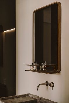 a bathroom sink sitting under a mirror next to a wall mounted faucet