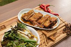 two plates of food on a cutting board with chopsticks next to one plate