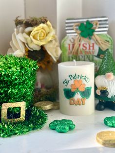 a st patrick's day candle surrounded by shamrocks and gold coins on a table