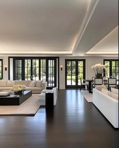 a living room filled with lots of white furniture and black accents in front of sliding glass doors