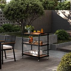 an outdoor table with drinks on it and two chairs next to it in the background