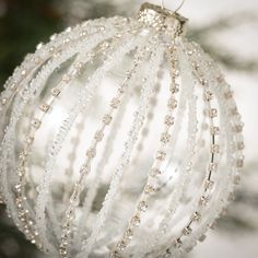 a glass ball ornament hanging from a christmas tree with beaded strands on it