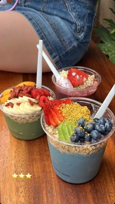 three desserts in plastic cups with strawberries and blueberries