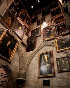 many paintings are hanging on the wall in an old building with stone walls and exposed ceilings