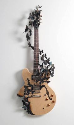 a guitar with butterflies on it hanging from the wall