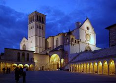 an old church lit up at night with people walking around the courtyard and onlookers