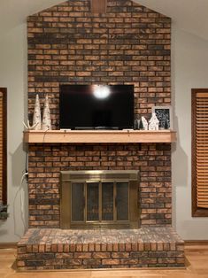 a flat screen tv mounted on top of a brick fireplace