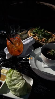 a table topped with plates of food next to glasses of wine and pizza on top of it