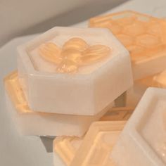 some soaps that are sitting on a white counter top, one is shaped like a flower and the other is shaped like a bee