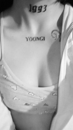 a woman with tattoos on her chest is wearing a white shirt and has the word yoongi written across her chest