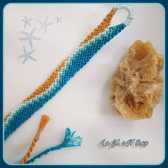 a blue and orange beaded bracelet next to a small piece of jewelry on a white surface