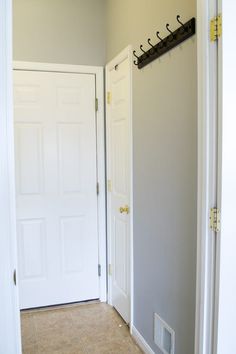 two white doors with hooks on them in a room that has tile flooring and beige walls