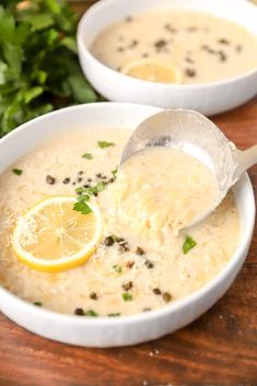 two white bowls filled with soup and garnished with lemon slices, parsley