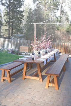 a picnic table set up with wine bottles and flowers in vases on the side