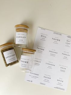 three jars of spices sitting on top of a white table next to a recipe book