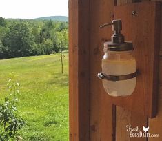 a soap dispenser hanging on the side of a wooden door in a field