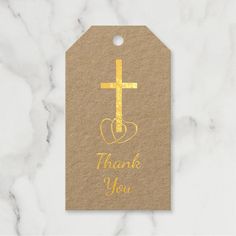 a thank you tag with a cross and heart in the middle on a marble background